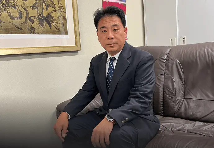 代表取締役中沢英俊がソファに座っている写真。